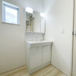 【洗面所】便利な三面鏡の洗面台です。シンプルかつ白で統一され、広々とした印象の空間です。